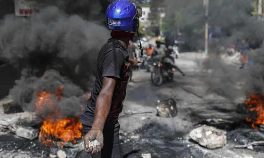 Un manifestante amenaza con arrojar piedras a los automovilistas que intentan pasar un bloqueo de carretera establecido por manifestantes antigubernamentales en Puerto Príncipe el jueves.
