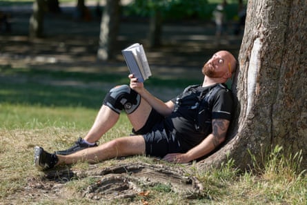 Ioan sits with his back against a tree, book in hand, eyes closed, blissful