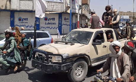Taliban fighters drive an Afghan national army vehicle through a street in Kandahar