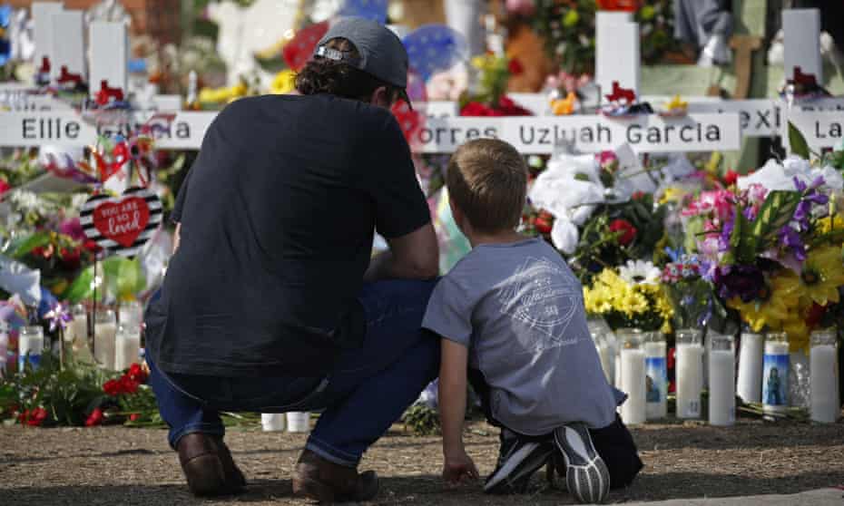 A man and a child pay their respects at a memorial outside Robb elementary school