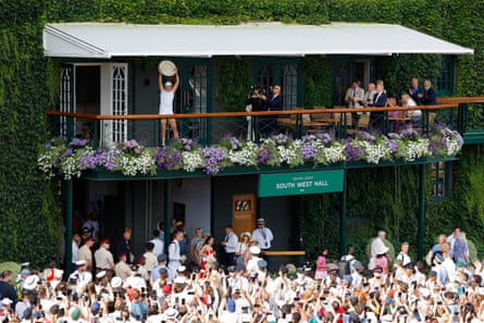 Iga Swiatek lifts the Venus Rosewater Dish on the balcony outside Centre Court.