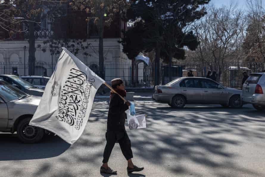 A boy selling Taliban flags walks down a Kabul road.