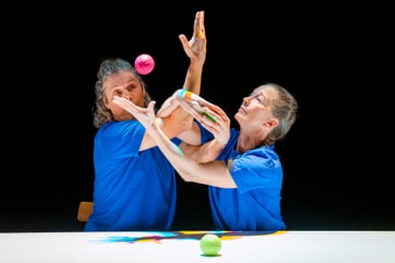 The jugglers’ arms are tangled as the balls fly in the air.
