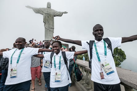 South Sudan’s athlete Yiech Pur Biel (R), Rose Nathike Lokonyen (C) based in Kenya, and Kenyan coach Joseph Domongole for the Refugee Olympic Team (ROT) pose in front of the statue of Christ the Redeemer as the statue appears in fog ahead of Rio 2016 Olympic Games in Rio de Janeiro, Brazil, on July 30, 2016. The International Olympic Committee (IOC) selects 10 refugee athletes to set a refugee’s team for the first time, to bring about hope to people displaced by conflicts or war in the world.