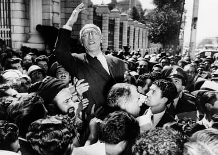 Mossadegh appears to smile and wave at the camera from the middle of a crowd