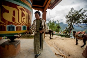 An elderly woman making the pilgrimage to Taktsang Monastery pauses for a moment of reflection at a prayer wheel