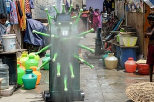 Residents watch as a coronavirus-themed robot sprays disinfectant in Chennai, India