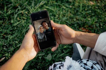 A man’s hands hold a phone showing an image of a man and a woman