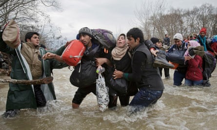 Migrants cross a river