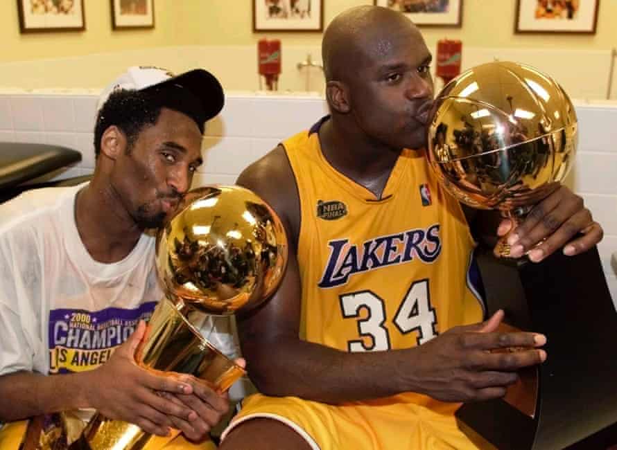 Los Angeles Lakers center Shaquille O’Neal (R) kisses the Most Valuable Player trophy as teammate Kobe Bryant kisses the NBA championship trophy as they celebrate in the locker room after winning the NBA Finals against the Indiana Pacers, June 19, 2000.