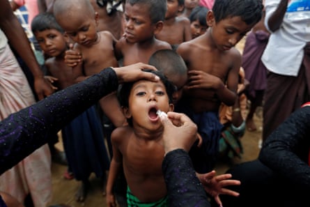 A child receives an oral vaccine in front of a group of other children