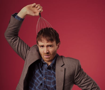 Looking at the camera, Ian Smith holds a scalp massager to his head