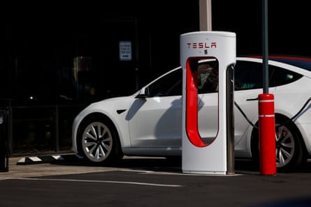 white sedan parked next to machine marked Tesla