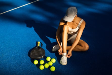 A woman tying her shoes on a pickleball court