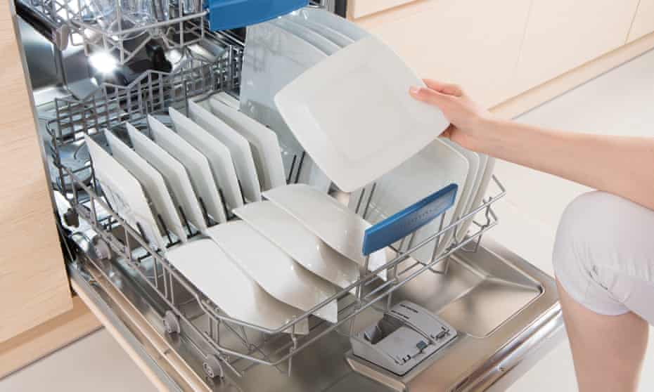 Woman using a dishwasher in a modern kitchen. 