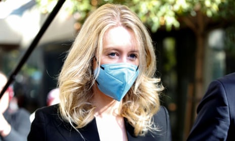 Elizabeth Holmes leaves a federal court in San Jose, California, wearing a black suit and blue face mask.