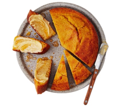 A plate of sliced cornbread – some of the slices are spread with butter – with a butter knife.