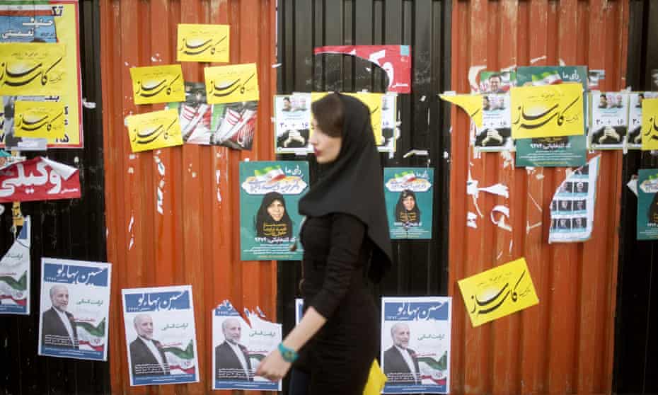 A woman walks past electoral posters in downtown Tehran.