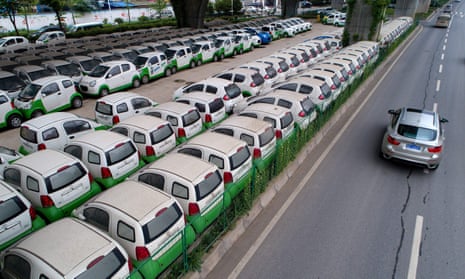 A car passes new electric vehicles in Wuhan, Hubei province