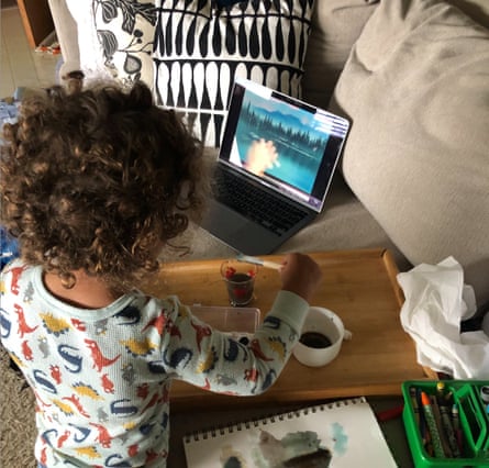a young child looks at a computer as he paints