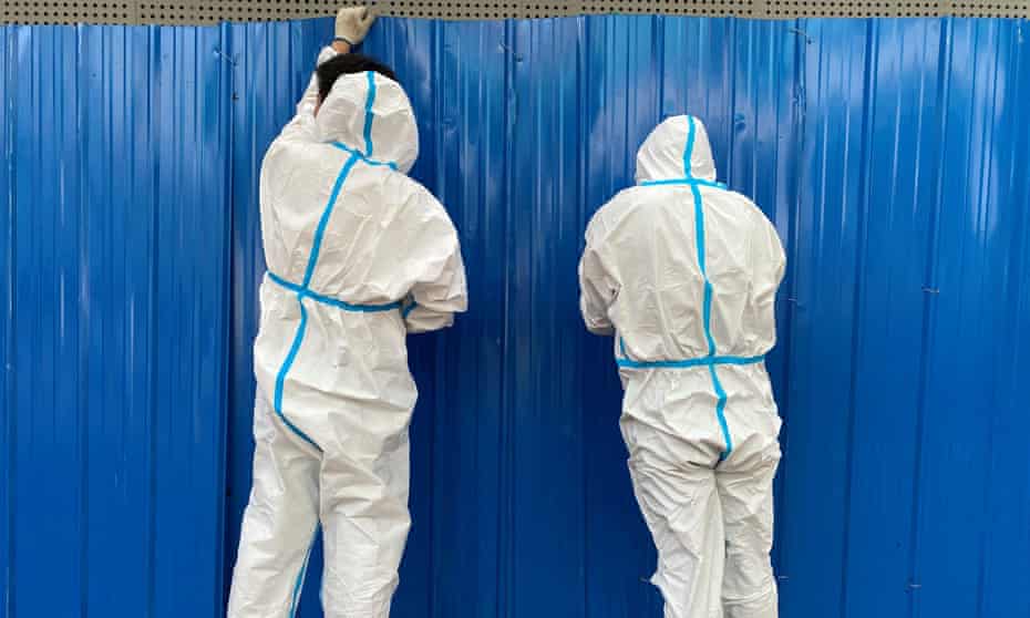 Workers in protective suits set up barriers outside a building, following the coronavirus disease outbreak, in Shanghai