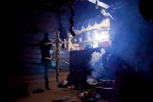 Clouded leopard skin hanging inside a kitchen belonging to a Naga headman, with a woman cooking nearby in 2011.
