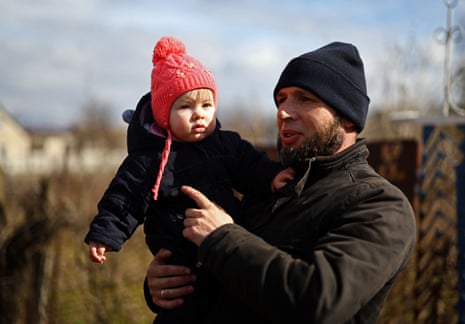 Oleksii Markelov holds his baby daughter, Kateryna, who was born during the Russian occupation, as he stands next to their house in Antonivka, Kherson region.