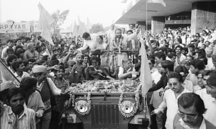 Narendra Modi waves from a vehicle to crowds of people who are holding banners, cheering and waving back