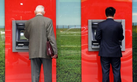 Two people use ATMs