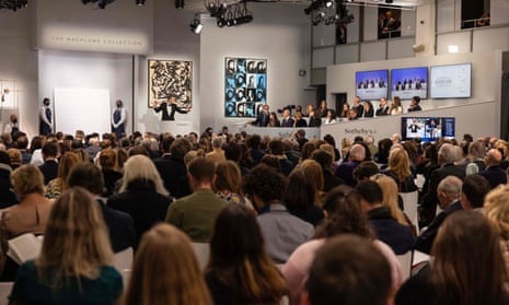 Auctioneer Oliver Barker leads an auction of the Macklowe Collection, alongside Andy Warhol's Sixteen Jackies (centre) at Sotheby's in New York