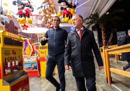 Steve Reed walking through an arcade and listening to a man walking next to him