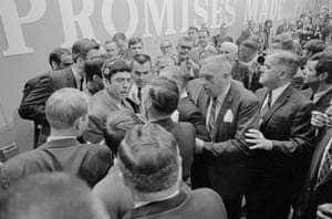 Reporting from the floor, CBS’ Dan Rather (left with headshot) is shoved by security agents at the Democratic National Convention after he tried to find out why a Georgia delegate, holding a Georgia standard, walked to the rostrum and then started out of the convention hall. Rather was shoved and then allegedly punched in the abdomen and knocked down. He said he was also told to “get the hell out.” Photo shows Rather talking to a group of security guards.