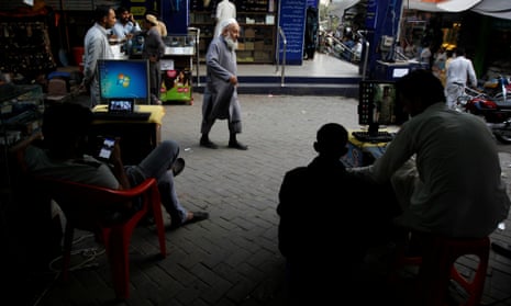 Men sit at their computers waiting to load media files into mobile phones for customers in the Abpara market in Islamabad, Pakistan