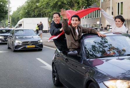 Morocco fans with a flag lean out of car on the streets on Amsterdam to celebrate the World Cup win over the Netherlands.