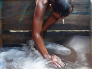Dimas Putra Hermawan, 17, an artisanal tin miner, washes glittery black sand of tin ore, as he works on a pontoon off the coast of Toboali