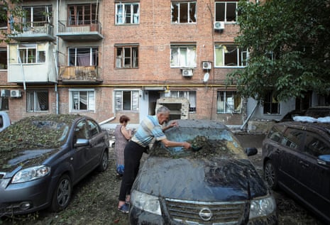 A man cleans a car damaged by a Russian military strike in Kharkiv.