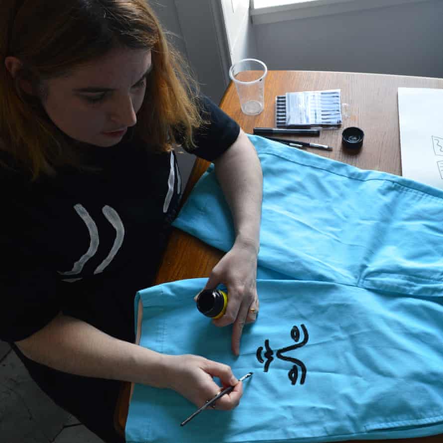 A woman drawing a face on a garment