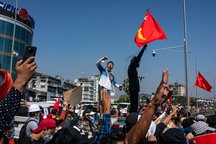 Protesters wave red National League For Democracy (NLD) flags and raise three-finger salutes in Yangon