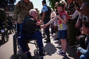 a US second world war veteran in a wheelchair shakes hands with a child lining the street