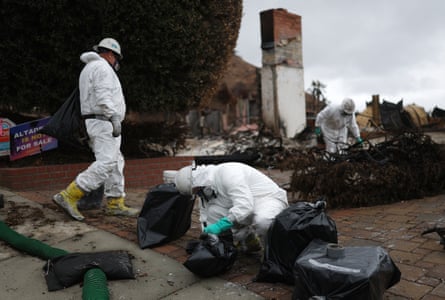 people in white suits cleaning up debris outside