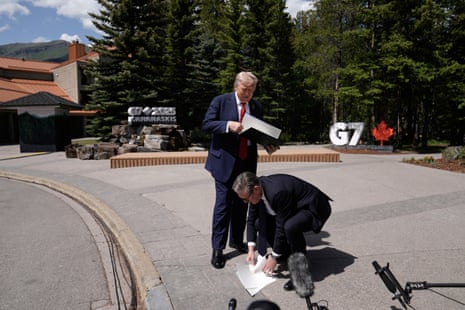 Starmer picking up some of the sheets of paper with the text of the agreement, after they were dropped by Trump.