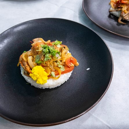 A plate holds a blue crab dish on sushi rice.