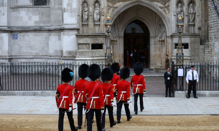 Soldiers in uniform walk into Westminster Abbey.