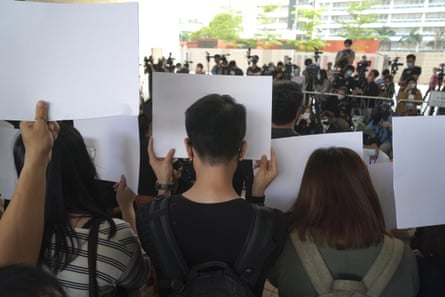 A group of protesters hold signs in front of their faces