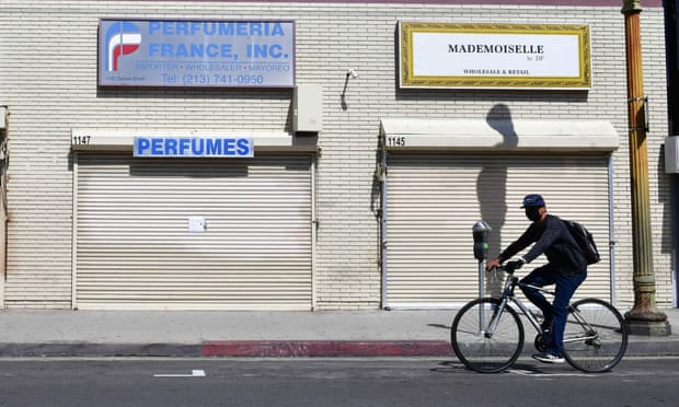 A person bikes past closed stores in Los Angeles, California. 