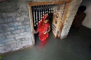 Mulher indiana vestida com traje de noiva em pé na água da enchente dentro de uma casa