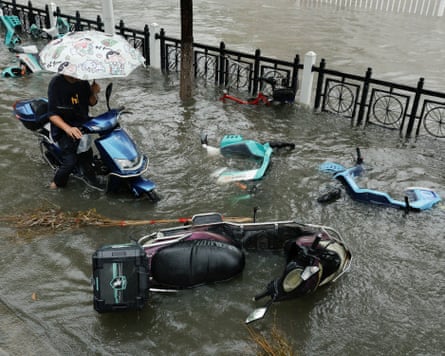 A person rides an electric scooter on a flooded street while avoiding fallen bicycles in Xiangyang, Hubei province.