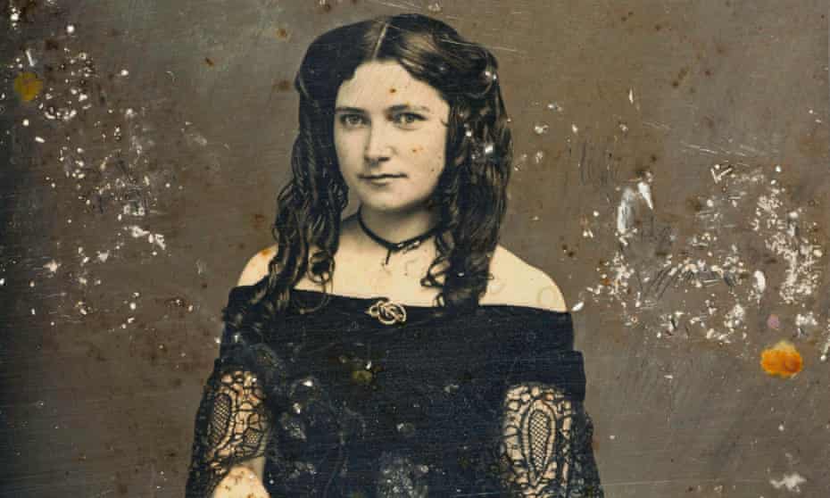 A young woman wearing a necklace, brooch and lace dress.