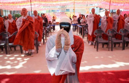 Gabi, the humanoid robot, puts its hands together with a group of Buddhist monks during the ordination ceremony