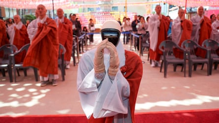 Humanoid robot puts its hands together pinch rows of monks down it